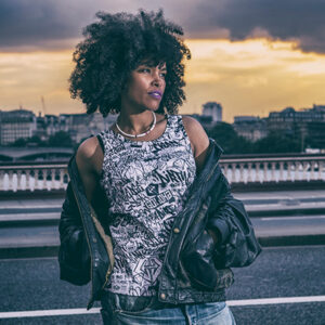 GOLOKA Dirty & Clean collection lookbook cover: model with an afro wearing a graffiti print tank top and leather jacket on a bridge at sunset