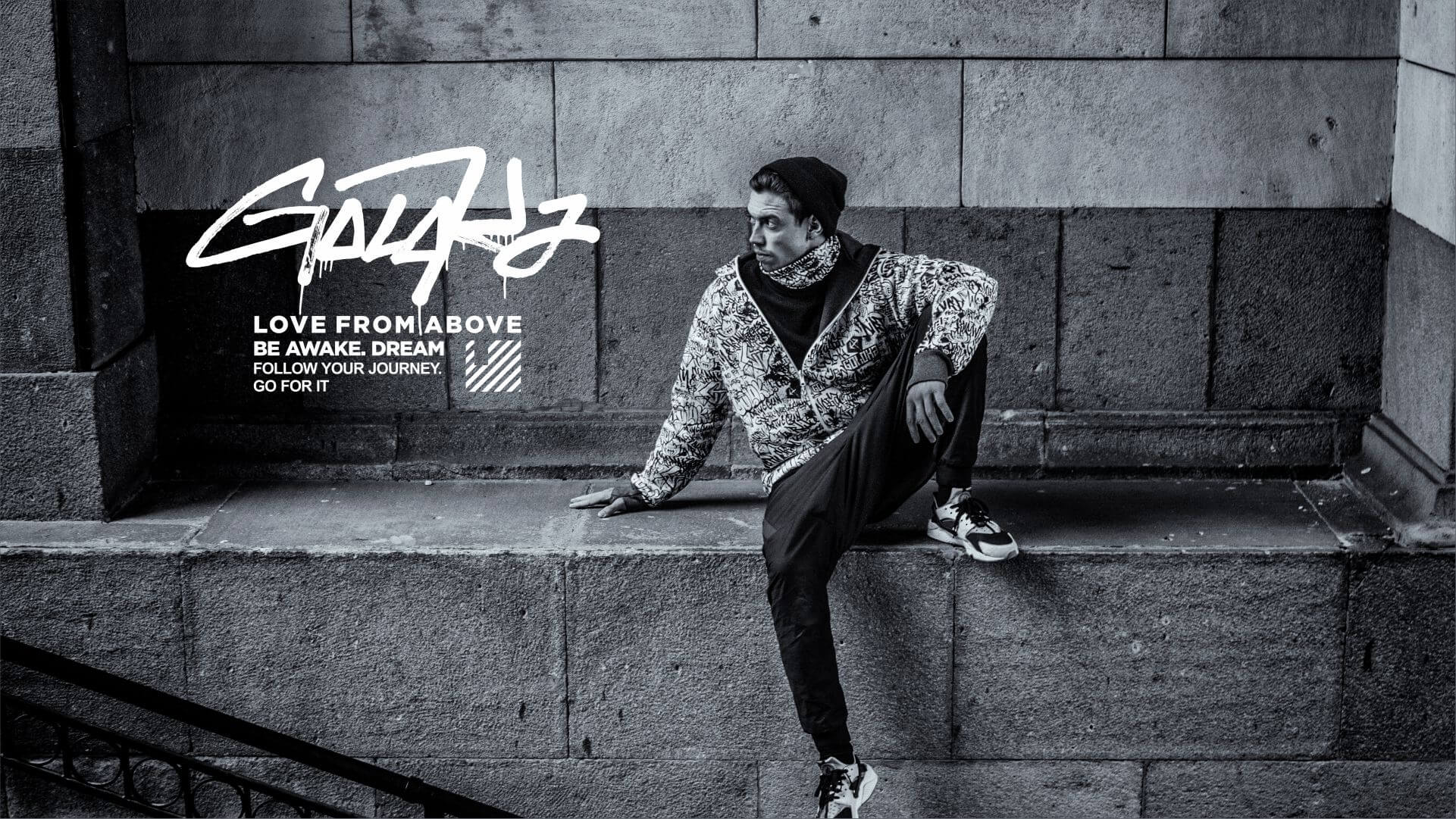 GOLOKA model in a printed jacket seated on stone steps, black and white urban photograph