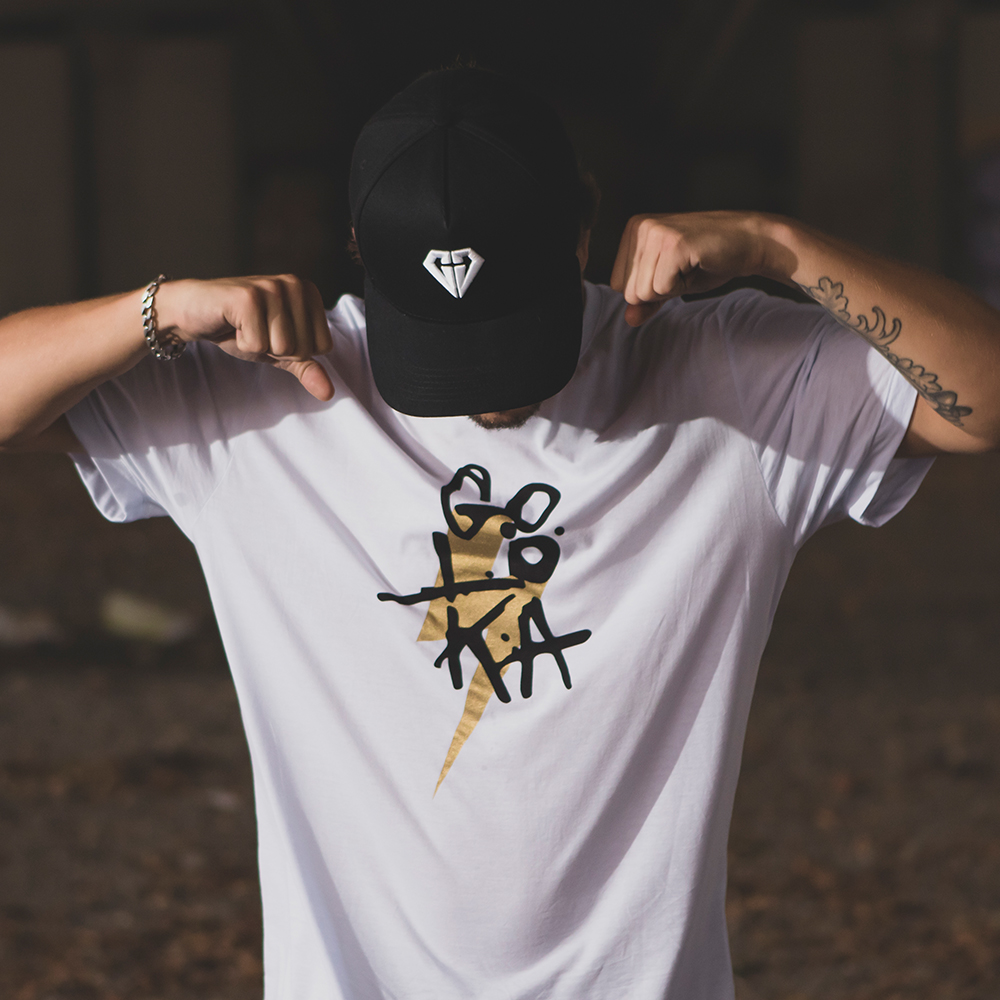 GOLOKA Soul'diers lookbook cover: model flexing in a white graphic t-shirt and diamond-logo cap
