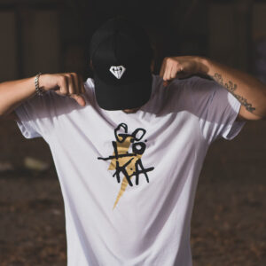 GOLOKA Accessories category tile: model wearing a black diamond-logo cap and white graphic t-shirt under a bridge